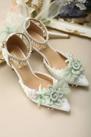 White high-heeled shoes with floral decorations on a beige background, Obroi