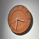 A minimalist terracotta orange round wall clock with white hands and Roman numeral hour markers, mounted on a light gray wall with a soft shadow, Obroi