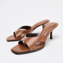 Pair of brown high-heeled sandals on a white background, Obroi