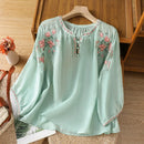 Light green blouse with floral embroidery on a wooden surface, Obroi