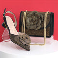 Black shoe and matching handbag with floral embellishments on a red background, featuring the brand , Obroi