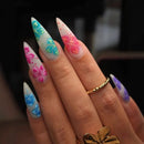 Hand with long, colorful floral nail art on a blurred background, Obroi