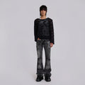 Person wearing a black sheer top and distressed black jeans on a light gray background, Obroi