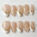 Ten almond-shaped press-on nails arranged in two rows on clear display stands against a white background. The nails have a glossy nude-beige top with a white French tip and decorative gold curved lines and small pearl accents, Obroi