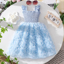 Light blue dress with floral skirt on a decorative surface with flowers and sunglasses, Obroi