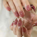 Close-up of hands with pink nail polish and gold tips on a neutral background, Obroi