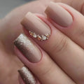 Close-up of a hand with beige and bronze nail polish on a neutral background