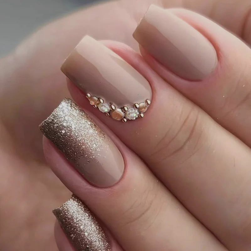 Close-up of a hand with beige and bronze nail polish on a neutral background