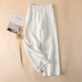 White pants on a beige background with a magazine and dried plant, Obroi