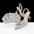Silver high-heeled shoes with a matching clutch and jewelry set on a white surface, Obroi