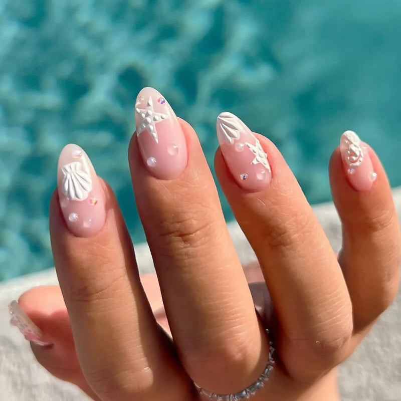 Hand with decorative nail art in front of a blurred pool background