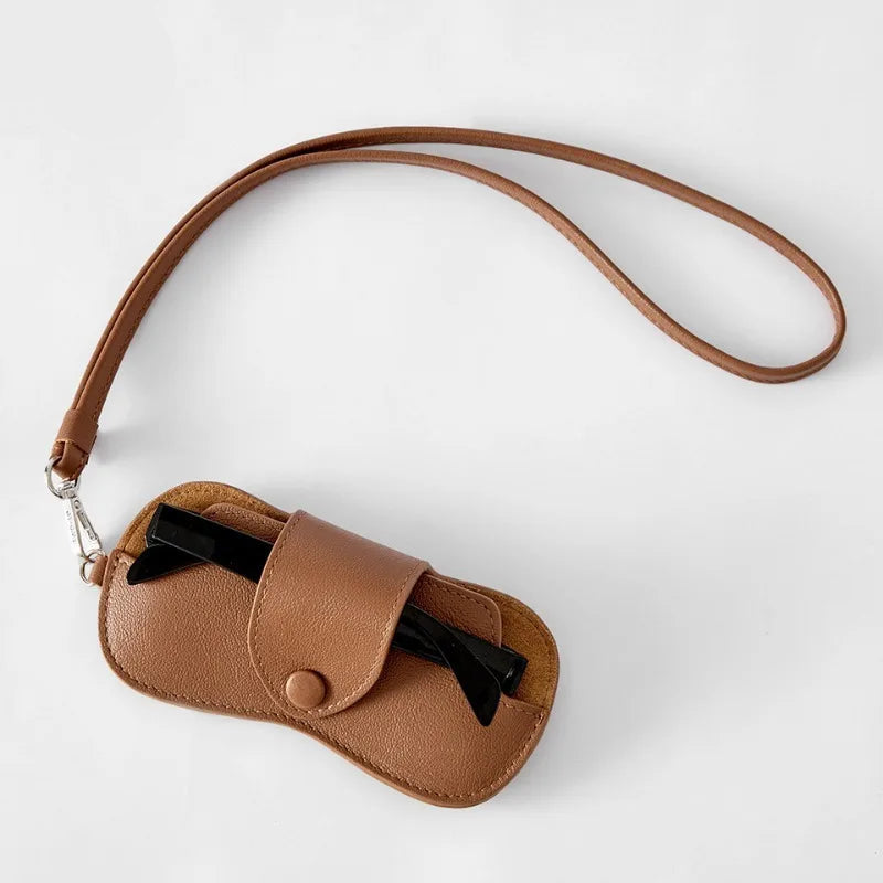 Brown leather case with a strap containing black hair clips on a white background, Obroi