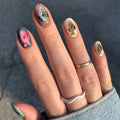 Nails with fish design held against a dark background, Obroi