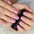 Close-up of hands with pink nail polish holding a red and black object, Obroi