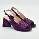 Purple high-heeled shoes with embellishments on a light gray background, Obroi