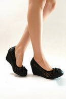 Black wedge shoes with lace detailing worn by a person on a white background, Obroi