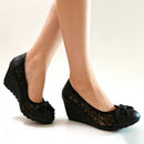 Black wedge shoes with lace detailing worn by a person on a white background, Obroi