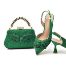 Green handbag and high-heeled shoes with floral details on a white background, Obroi
