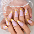 Nails with pink and yellow design held by a person wearing a white lace garment, Obroi