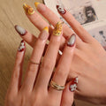 Close-up of a hand with intricately designed nails and gold rings, Obroi