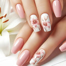 Nails with floral design and pink polish held against a white flower background, Obroi