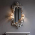 Decorative mirror with floral frame on a wall with two lamps, Obroi