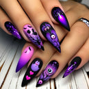 Halloween-themed nail art with purple, black, and pink designs on a wooden surface, Obroi
