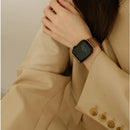 A close-up of a person wearing a smartwatch with a black rectangular face and a metallic rose gold mesh band, styled with a beige blazer, Obroi