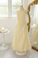 Yellow dress on a mannequin in front of a decorative mirror with floral arrangements, Obroi