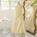 Yellow dress on a mannequin in front of a decorative mirror with floral arrangements, Obroi