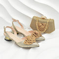A pair of gold glitter slingback heeled sandals with large 3D fabric flower embellishments on the toes, shown alongside a matching gold clutch handbag with a chain strap, set against a white background with wavy lines, Obroi