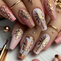 Nails with intricate gold and rose gold designs on a light wooden surface, Obroi
