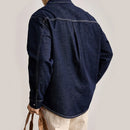 Person wearing a dark blue denim shirt on a plain background, Obroi