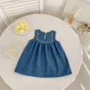 Blue denim dress on a round white table with decorative items, Obroi