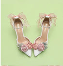 White high-heeled shoes with pink floral decorations on a light green background, Obroi