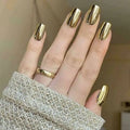 Hand with gold nail polish and a gold ring on a neutral background, Obroi