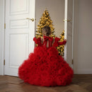 Child in a red dress standing in front of a Christmas tree, Obroi