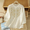 White blouse with floral embroidery on a wooden shelf, Obroi