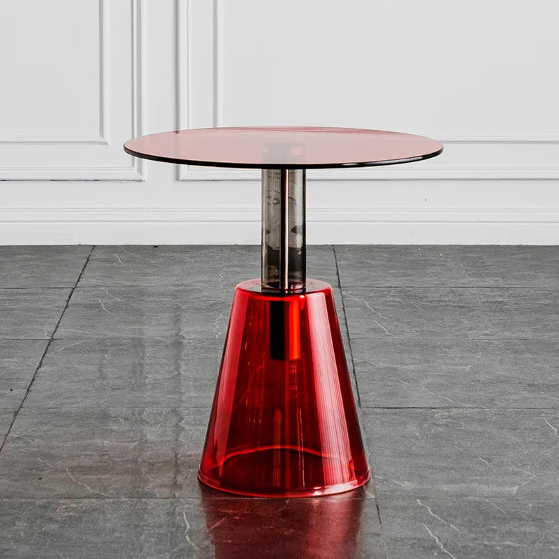 Round glass table with a red transparent base on a gray floor, Obroi