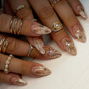 Close-up of hands with decorative nails and rings on a neutral background, Obroi