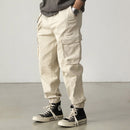 Person wearing beige cargo pants and black high-top sneakers on a plain background