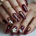 Maroon nails with floral and geometric gold designs on a neutral background, Obroi