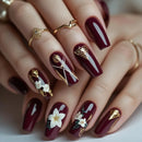 Maroon nails with floral and geometric gold designs on a neutral background, Obroi