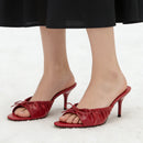 Red high-heeled shoes worn with a black skirt on a white background, Obroi