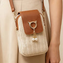Woven handbag with brown leather flap and cat ear charm held by a person wearing a beige outfit, Obroi
