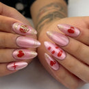 Pink nail art with red hearts and gold accents on a neutral background, Obroi