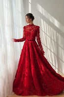 Woman wearing a red lace evening gown standing against a white curtain, Obroi