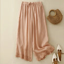 Pink pants with lace trim on a light beige background, accompanied by a woven bag and shoes, Obroi