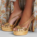 Gold high-heeled platform sandals worn with a floral dress, Obroi