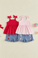 Two toddler girls' sleeveless top-and-shorts sets laid flat on a light beige background. The left set is bright red with matching red bow shoulder straps and denim shorts with strawberry embroidery and ruffle hems, Obroi